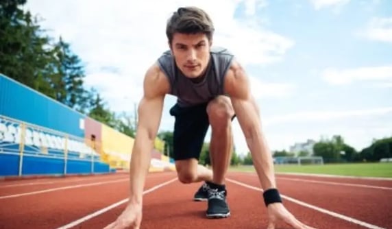 homme sportif de face mains au sol sur 1 piste au départ d''1 course de vitesse