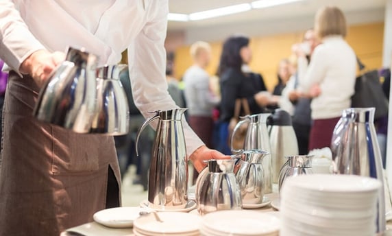 a waitress's hand is holding a tray with plates and cups