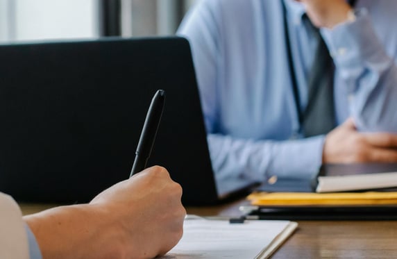 a man sitting at a table with a notebook and pen