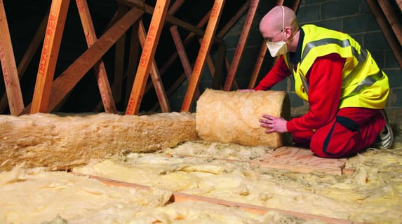 a man in a yellow vest and safety vest is working on a roof