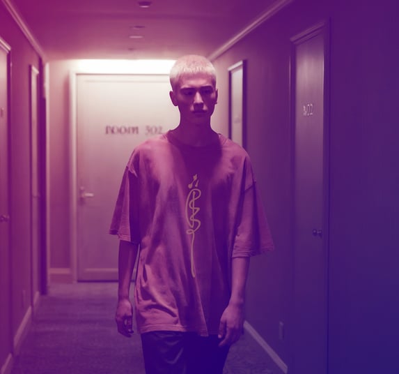 male model in oversized talisman T-shirt by FuluTee walking down dimly lit hallway with surreal, dreamy lighting.