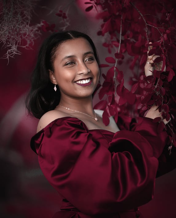 a woman in a red dress smiling and holding a flower