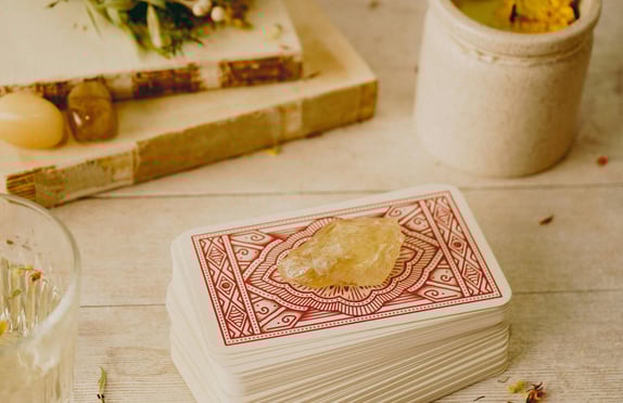 carta baralho cigano com pedra de cristal levemente amarelo e outras pedras e livros antigos a volt