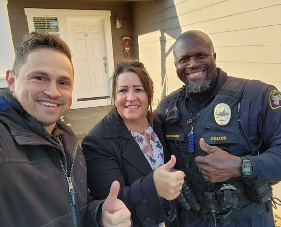Alex standing with home owners next to their home. A happy husband and wife.