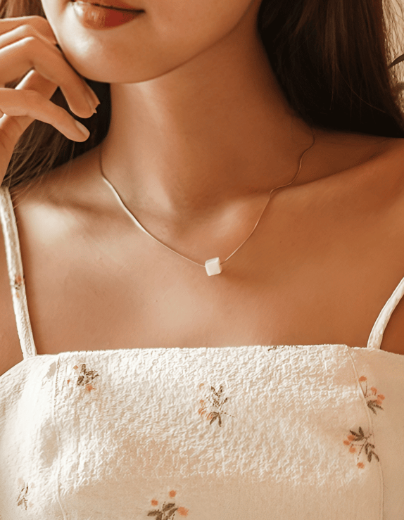 a woman in a white dress waering pearl pendant and earring
