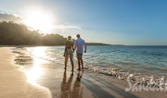 a couple holding hands and walking on the beach