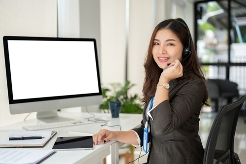 customer support service agent with a headset sits at her desk in the office