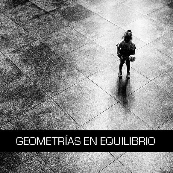 Fotografía en blanco y negro de una niña con un balón sobre una gran superficie geométrica