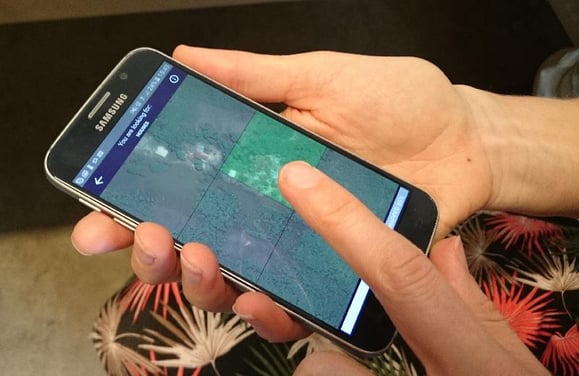 Person using MapSwipe on smart phone which just involves tapping an image for a goal such as a road or building present.
