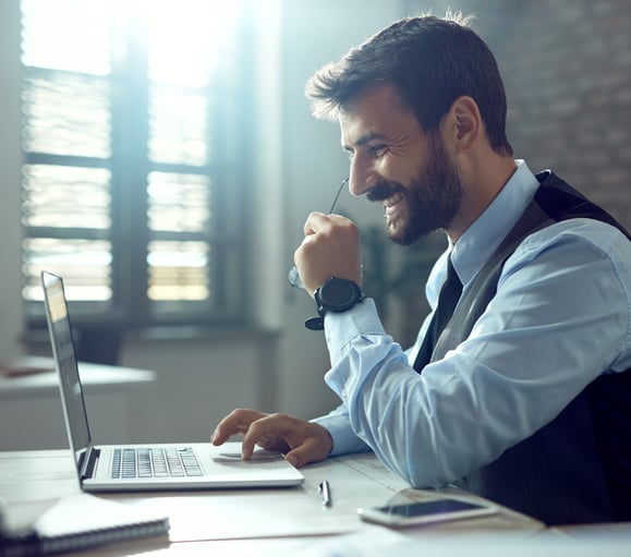 Homem sorrindo olhando para tela do notebook e mexendo do trackpad