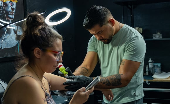 a man and woman getting their tattoos done