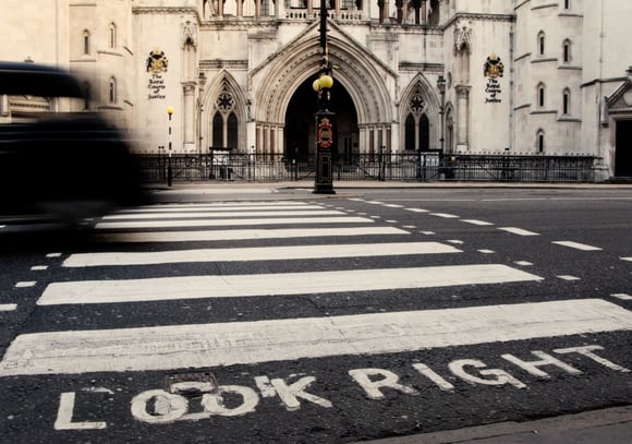 London taxi crossing a zebra pedestrian crossing in front of the Royal Courts of Justice, with “LOOK RIGHT” painted on road