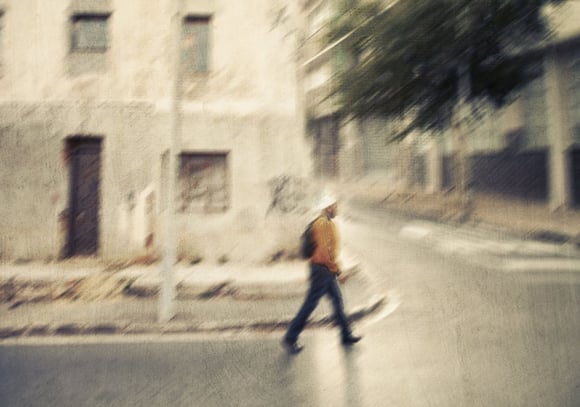 Early morning street scene in Woodstock, Cape Town, with soft sunlight illuminating a single pedestrian crossing the road