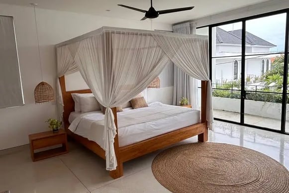 Cozy bed facing tropical greenery in a modern Balinese villa
