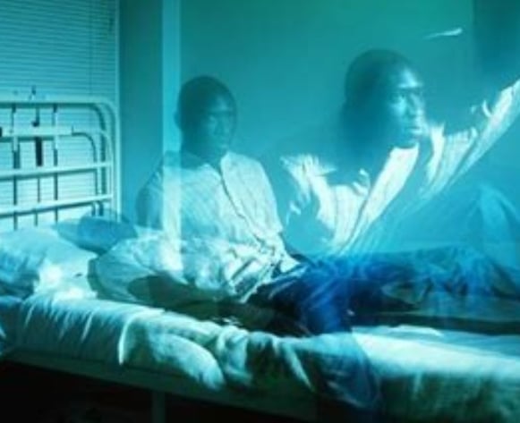two people sitting on a bed in a hospital room