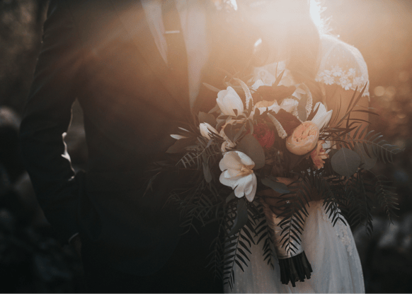 a bride and groom holding a bouquet of flowers