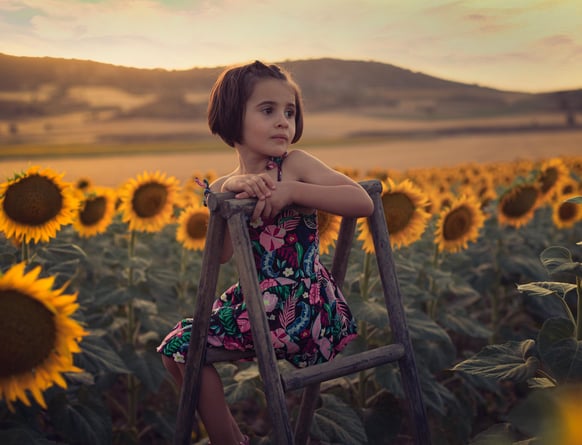 a little girl sitting on a chair in a field