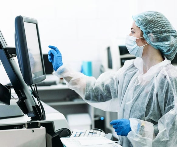gowned and gloved female doctor interfacing with medical equipment