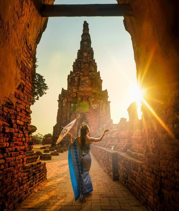 femme devant un temple qui porte une longue robe bleue et un parasol dans sa main