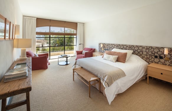 Bright bedroom suite at Villa La Gratitud with garden views, cozy seating, and soft natural tones.