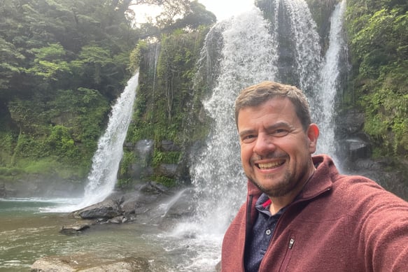 Picture of the site owner standing in front of a waterfall in Japan