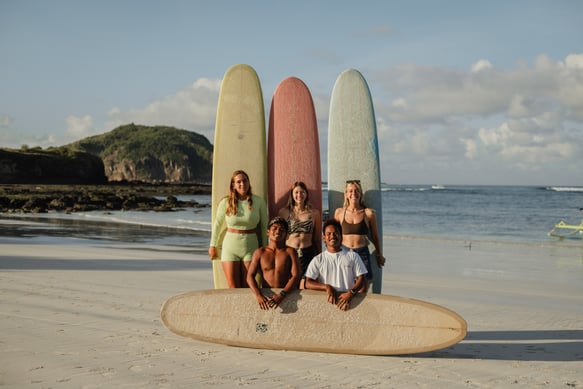 Surf school Kuta Lombok team and students posing with surfboards on the beach in Indonesia