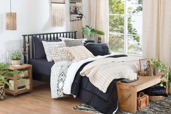 uma cama com uma cama preta e um banco de madeira