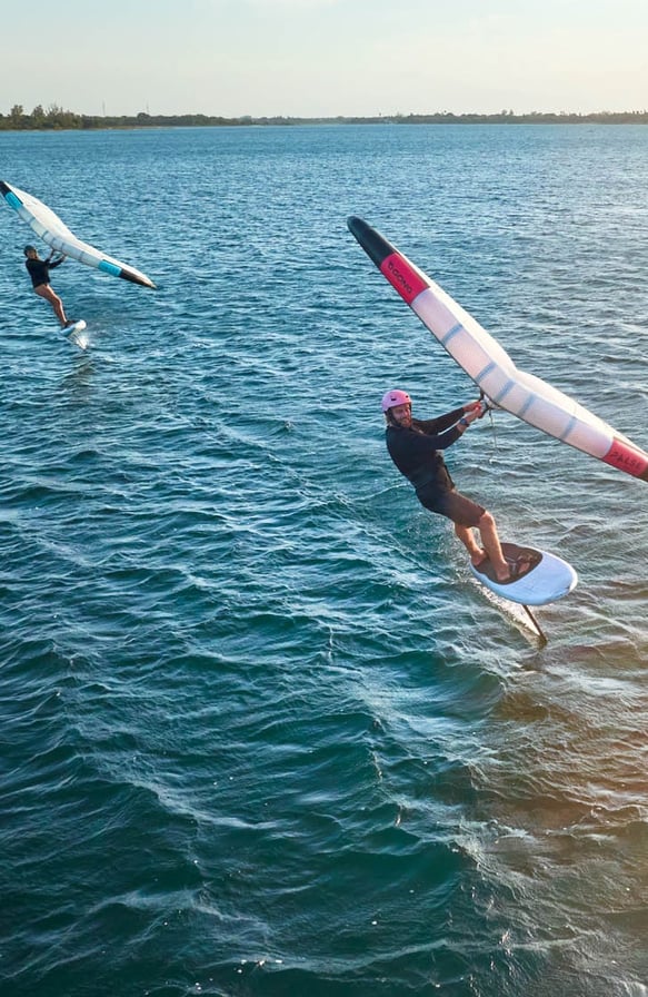 Saulėlydis Svencelėje su wing foil sportininku virš vandens paviršiaus