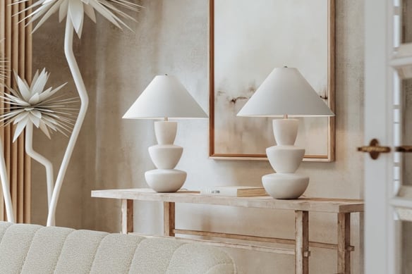 a living room with a couch and a table and white table lamps 