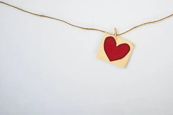 a heart shaped piece of paper with a red heart hanging from a string