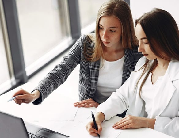 two women sitting at a desk discussing business