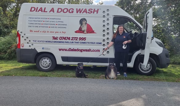 Suzy and two of her dogs stand outside her custom build dial a dog wash van