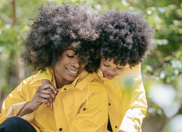 a woman and a young child wearing yellow rain jackets sitting on a bench smiling together