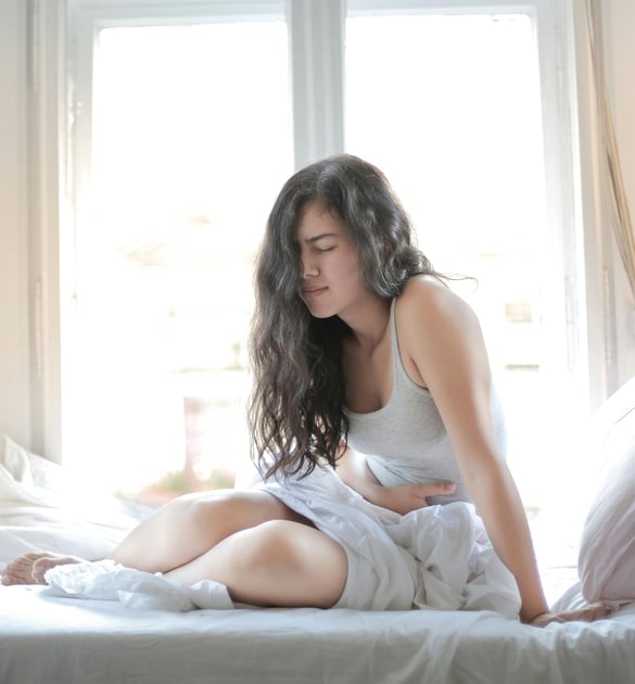 a woman sitting on a bed with a white sheet