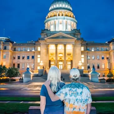 Couple standing in front of the Idaho state capital building at sundown.