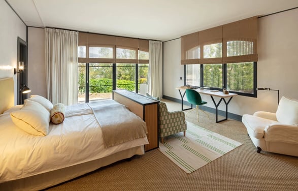Bright bedroom suite at Villa La Gratitud with garden views, cozy seating, and soft natural tones.