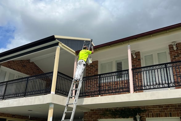 a man in a yellow safety vest is painting a house