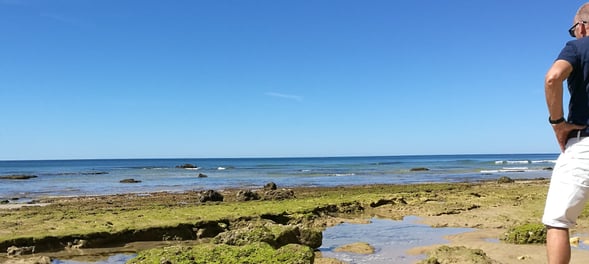 Man die geniet van de prachtige kustlijn van Praia do Barranco