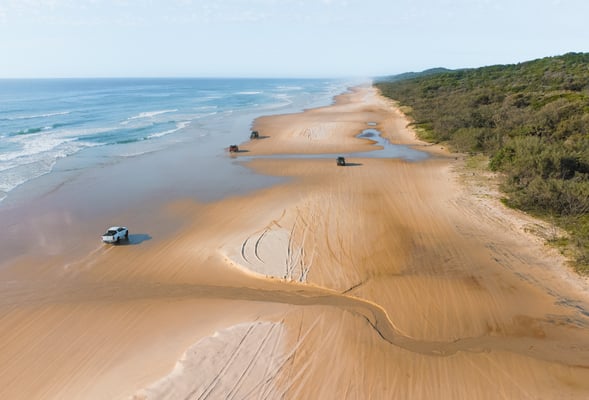 Fraser island beach drone shot, 4WD cars driving on the beach on a sunny day