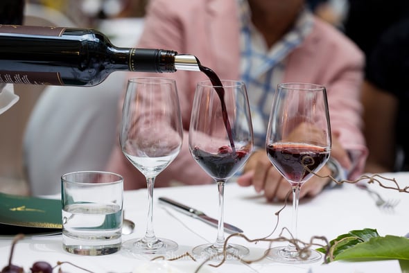 Der Kellner schenkt Rotwein in ein Glas ein.