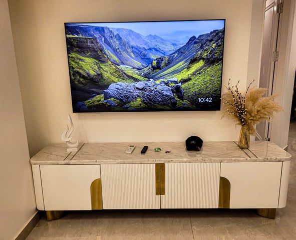 A modern and elegant living room setup featuring a wall-mounted TV, a sleek white and gold marble-to