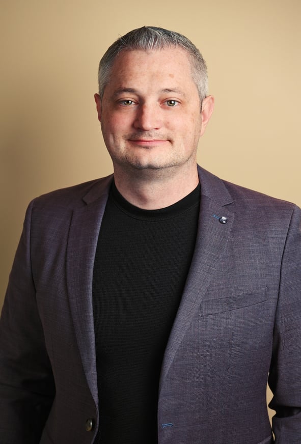 a man in a suit and black shirt with indoor lighting