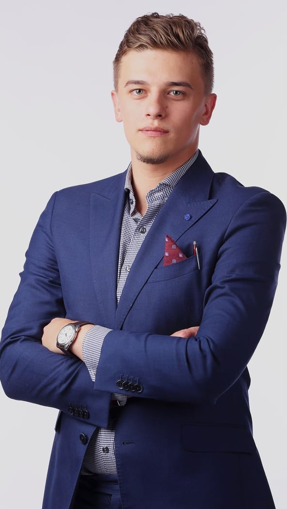 Young lawyer dressed in a sharp navy blue suit, with arms crossed, representing expert legal services in Spain.