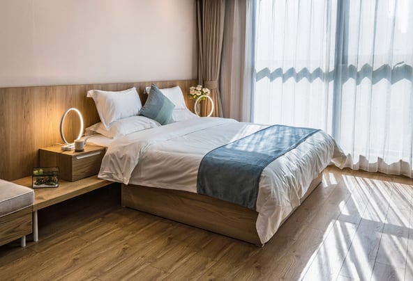 Chambre avec lit double draps bleus et parquet
