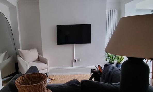 TV mounted on a wall in a living room with surface trunking. Camden