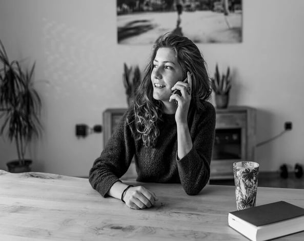 Femme souriante au téléphone représentant un échange humain et bienveillant