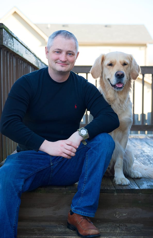 a man sitting on a wooden deck next to his pet the Golden Retriever