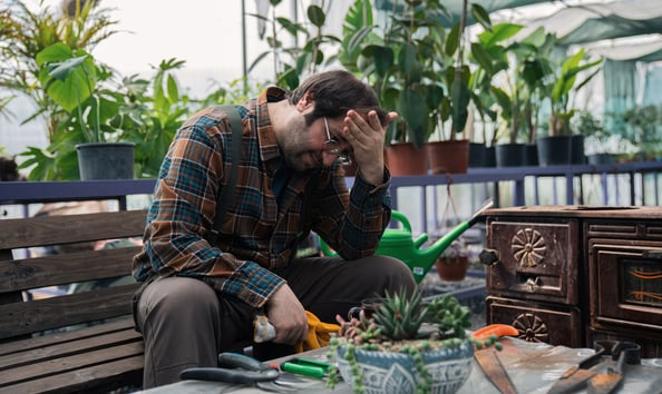 Frustrated gardener rubbing his head