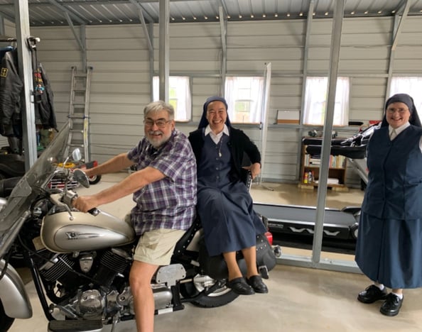 Motorcyclist giving rides to Catholic nuns.