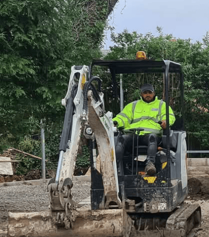 Mini digger with driver at work in Winchmore hill London